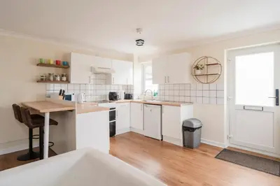 a kitchen with white cabinets and a wooden table at Ely Stays Flat 1 in Ely