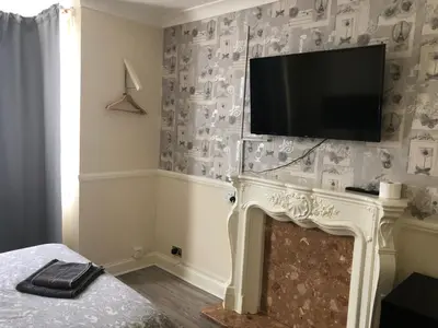 a living room with a fireplace with a flat screen tv above it at Ac Lounge 36 Room A in Rochford