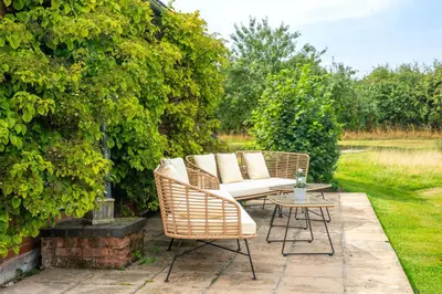 a patio with wicker chairs and a table at Cutbush Farm House in Hingham