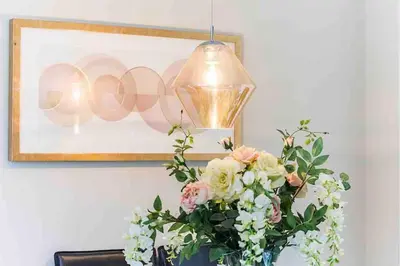 a vase of flowers sitting on a table with a picture at By Buildersbeds - Colne House 4 bedrooms in Harold Wood