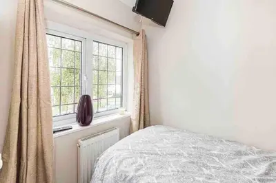 a bedroom with a bed and two windows at By Buildersbeds - Colne House 4 bedrooms in Harold Wood