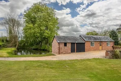 a brick house with a pond in front of it at The Old Woodstore in Sudbury