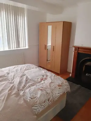an unmade bed in a bedroom next to a fireplace at At Apex House in Horndon on the Hill