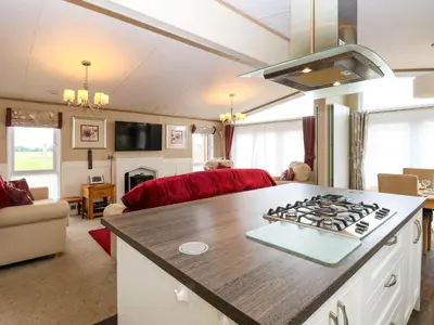 a kitchen and living room with a stove top at Lodge 26, Fishing Lakes in Stowmarket