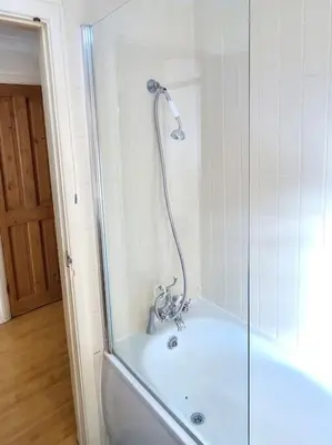 a bath tub with a shower in a bathroom at Accessible Flat Greater London in Upminster