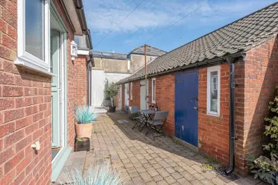 a brick house with a blue door and a patio at Beachcomber, Aldeburgh in Aldeburgh