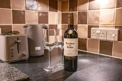 a bottle of wine sitting next to a wine glass at The Falcon's Nest - Central in Bury Saint Edmunds