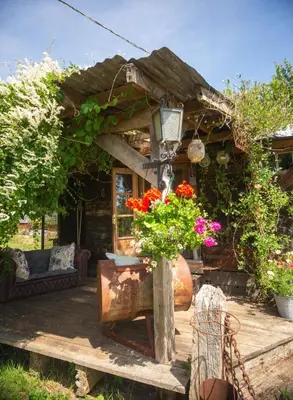 a small house with flowers in a garden at Little Lodge Glamping in Halesworth
