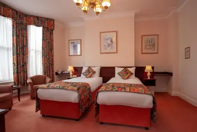 a hotel room with two beds and a chandelier at Arundel House Hotel in Cambridge