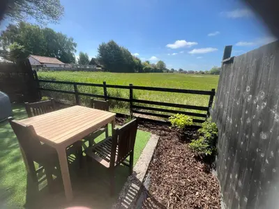 a wooden table and chairs next to a fence at Lavender Lodge - Pool and Hot Tub with sunset views over open fields in Wymondham