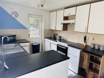 a kitchen with white cabinets and black counter tops at Kinlett close in Mile End
