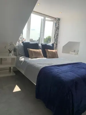 a bedroom with a large bed with blue sheets and a window at Cosy Studio Apartment in Leigh-on-Sea, Close to Bell Wharf Beach & Adventure Island in Leigh-on-Sea