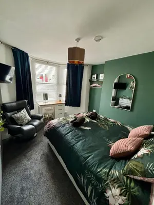 a bedroom with a bed and a chair and a mirror at Stylish and Chic Seaside Apartment in Southend-on-Sea