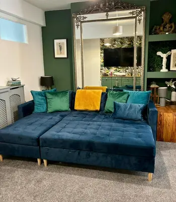 a blue couch in a living room with a mirror at Stylish and Chic Seaside Apartment in Southend-on-Sea