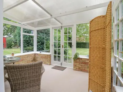 an orangery with windows and a table and chairs at West View in Thetford
