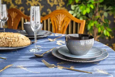 a table with a blue table cloth with a cup and forks at Luxury 2 Bed Manor House Hot Tub Cinema Room SkyTV in Saffron Walden