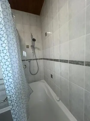 a bathroom with a bath tub and a shower curtain at Truehome Close to Stansted Airport in Harlow