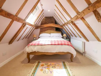 a bedroom with a large bed in a attic at Brook Cottage in Saxmundham