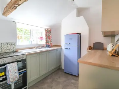 a kitchen with a refrigerator and a sink at Brook Cottage in Saxmundham