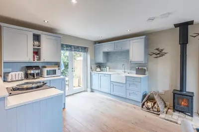 a kitchen with blue cabinets and a stove at Captain's Quarters, a ground floor apartment in Aldeburgh in Aldeburgh