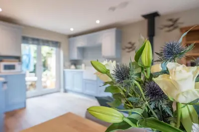 a vase with flowers on a table in a kitchen at Captain's Quarters, a ground floor apartment in Aldeburgh in Aldeburgh