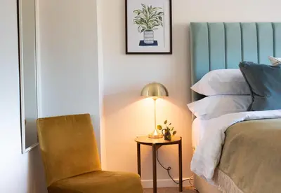 a bedroom with a bed and a chair and a lamp at 3 Bedroom House with Courtyard Garden and Parking in Chesterton