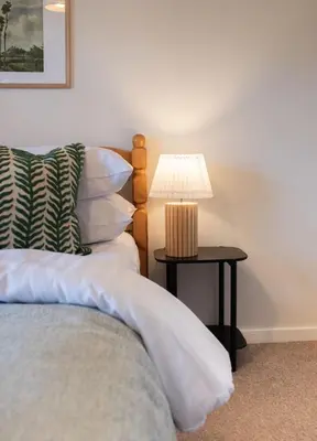 a bed with a side table with a lamp on it at 3 Bedroom House with Courtyard Garden and Parking in Chesterton