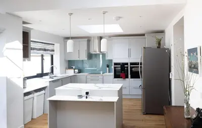 a kitchen with white cabinets and a stainless steel refrigerator at 3 Bedroom House with Courtyard Garden and Parking in Chesterton