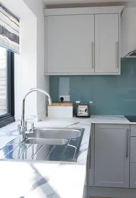 a kitchen with a sink and white cabinets at 3 Bedroom House with Courtyard Garden and Parking in Chesterton