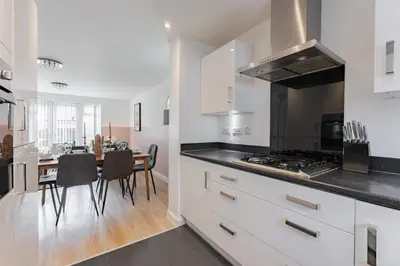 a kitchen with white cabinets and a table with chairs at Stylish & Chic 3 bed House in Cambourne