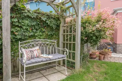a bench sitting under a gazebo in a garden at The Poppies, a stylish Aldeburgh holiday home in Aldeburgh