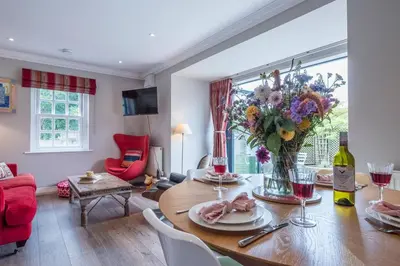 a living room with a table with a vase of flowers at The Poppies, a stylish Aldeburgh holiday home in Aldeburgh