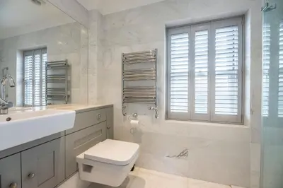 a white bathroom with a toilet and a sink at The Poppies, a stylish Aldeburgh holiday home in Aldeburgh