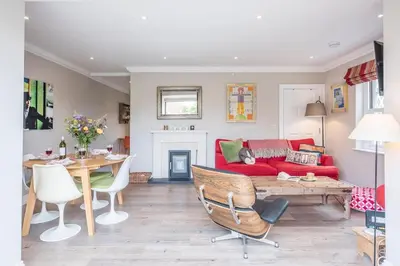 a living room with a red couch and a table at The Poppies, a stylish Aldeburgh holiday home in Aldeburgh