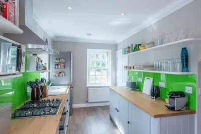 a kitchen with green and white cabinets and a stove at The Poppies, a stylish Aldeburgh holiday home in Aldeburgh