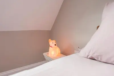 a stuffed animal sitting on a night stand next to a bed at The Poppies, a stylish Aldeburgh holiday home in Aldeburgh
