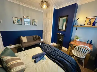 a bedroom with blue walls and a bed and a chair at Stylish and artistic flat in Southend on Sea - 2 Double Bedrooms, Free on-street parking in Southend-on-Sea