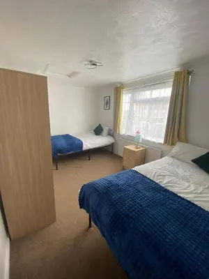 a bedroom with two beds and a window at Sleek 3-Bed Home in Harlow, Essex in Great Parndon
