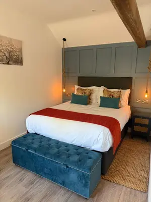 a large bed with a blue ottoman in a bedroom at The Stables Kersey Mill in Whatfield