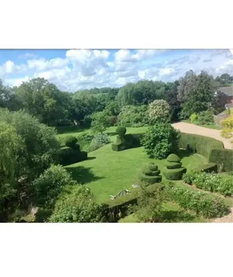 a view of a garden with a bench and trees at The Stables Kersey Mill in Whatfield