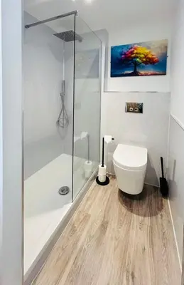 a white bathroom with a shower and a toilet at The Stables Kersey Mill in Whatfield