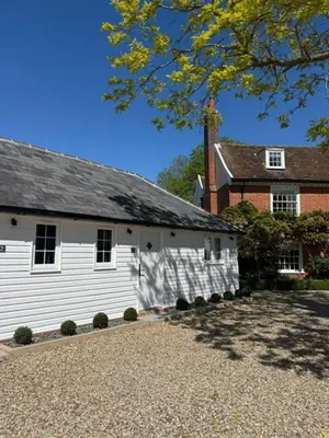 a large white building with a brick house at The Stables Kersey Mill in Whatfield