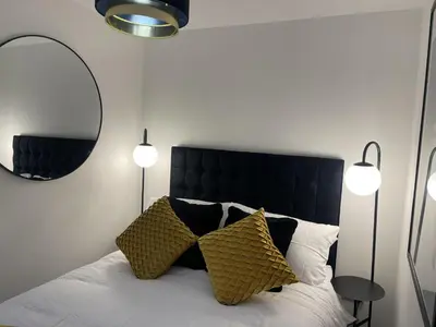 a bedroom with a bed with a black headboard and two lights at Modern-luxury 1bedroom-EnsuiteBathroom-Garden-Wifi in Basildon