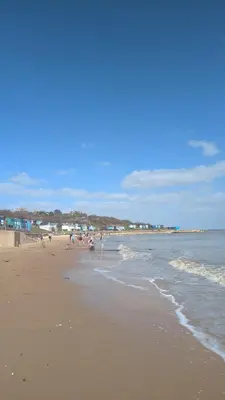 a beach with people on the sand and the water at Beach Walk Cottage in Walton-on-the-Naze