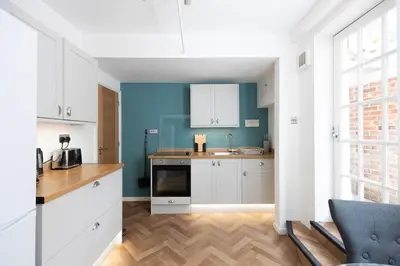 a kitchen with white cabinets and a blue wall at Central Medieval Grid Unique home with Gated parking in Bury Saint Edmunds