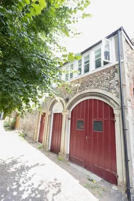 a building with a red garage door and a house at Central Medieval Grid Unique home with Gated parking in Bury Saint Edmunds