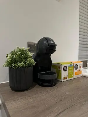 a black coffee maker next to a plant and boxes at The Snug - Town Centre Apartment in Bishops Stortford