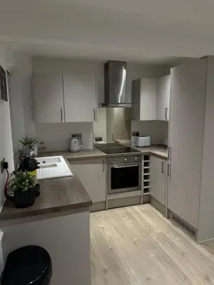 a kitchen with white cabinets and a stove top oven at The Snug - Town Centre Apartment in Bishops Stortford