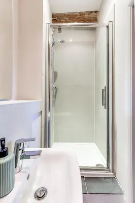 a bathroom with a shower and a white sink at Harestreet Farm Barns, The Dairy, Parlour and Creamery in Cottered