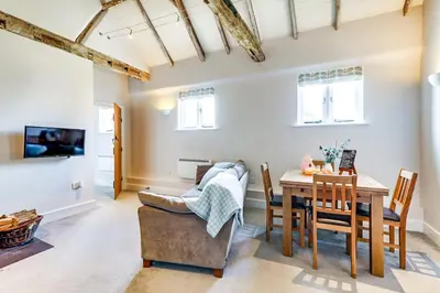 a dining room and living room with a table and chairs at Harestreet Farm Barns, The Dairy, Parlour and Creamery in Cottered